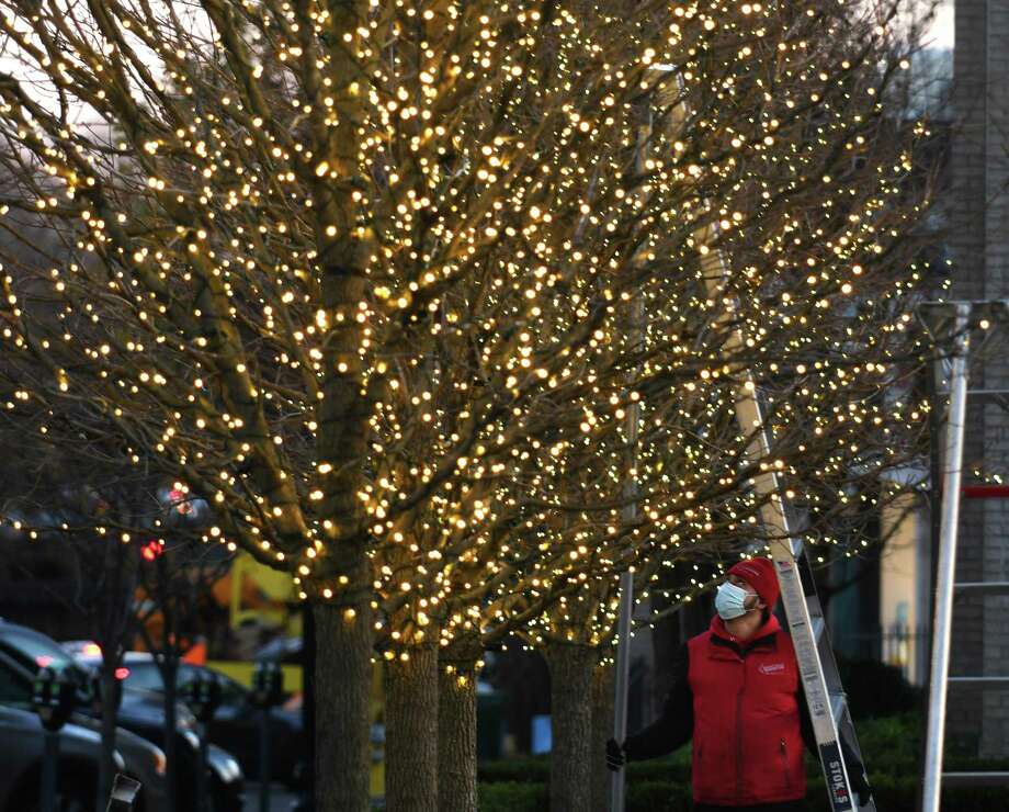 Marvin Velasquez, of Christmas Lighting Company, installs strings of lights on the trees outside Restoration Hardware in downtown Greenwich, Conn. Tuesday, Nov. 24, 2020. Photo: Tyler Sizemore / Hearst Connecticut Media / Greenwich Time