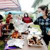 Jacqueline Hays uncovers onne of the main attractions as she, neighbors and friends hold a socially distanced backyard picnic to safely celebrate Thanksgiving in the joint backyard of their Old Town residences. Photo taken Thursday, November 26, 2020 Kim Brent/The Enterprise