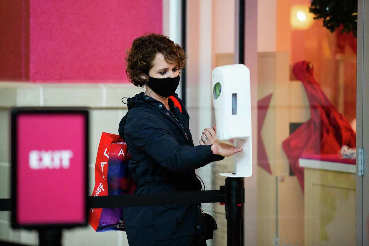 Before entering American Girl at Memorial City Mall, a shopper gets hand sanitizer, Friday, Nov. 27, 2020, in Houston.