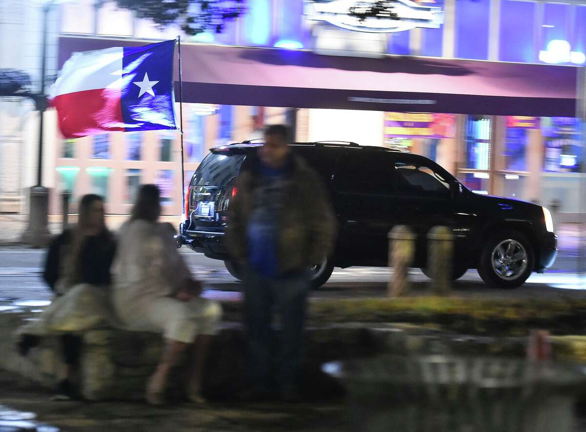 A cardisplaying the Texas flag honks its horn as it passes the Alamo Saturday night prior to a "social Gathering" to protest the San Antonio curfew.