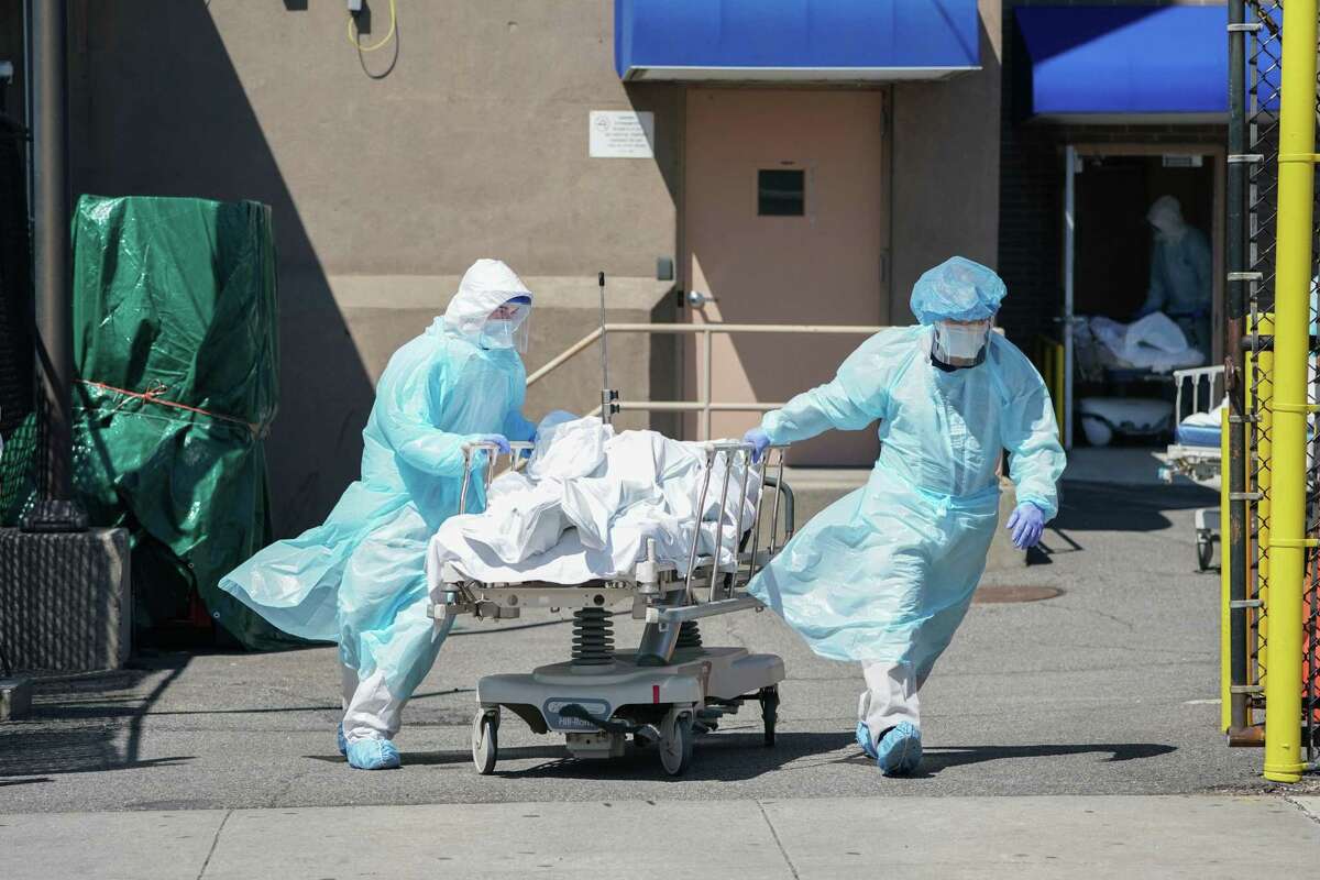 (FILES) In this file photo bodies are moved to a refrigeration truck serving as a temporary morgue at Wyckoff Hospital in the Borough of Brooklyn on April 6, 2020 in New York. - America should prepare for a "surge upon a surge" in coronavirus cases as millions of travelers return home after the Thanksgiving holiday, top US scientist Anthony Fauci warned on November 29, 2020. The United States is the worst-affected country, with 266,074 Covid-19 deaths, and President Donald Trump's administration has issued conflicting messages on mask-wearing, travel and whether the outbreak is under control. (Photo by Bryan R. Smith / AFP) (Photo by BRYAN R. SMITH/AFP via Getty Images)