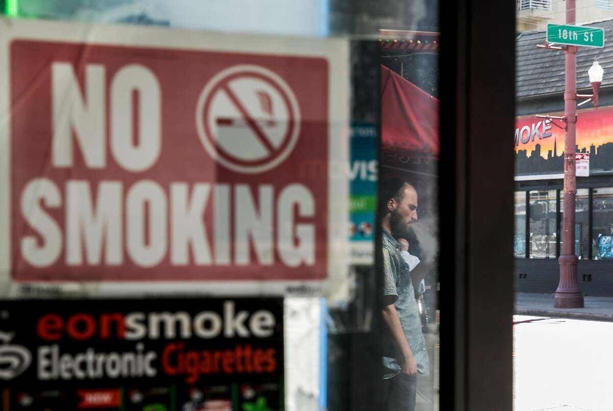 A man smokes an e-cigarette outside of The Town Smoke Shop in the Mission district of San Francisco, Calif. Thursday, March 21, 2019.