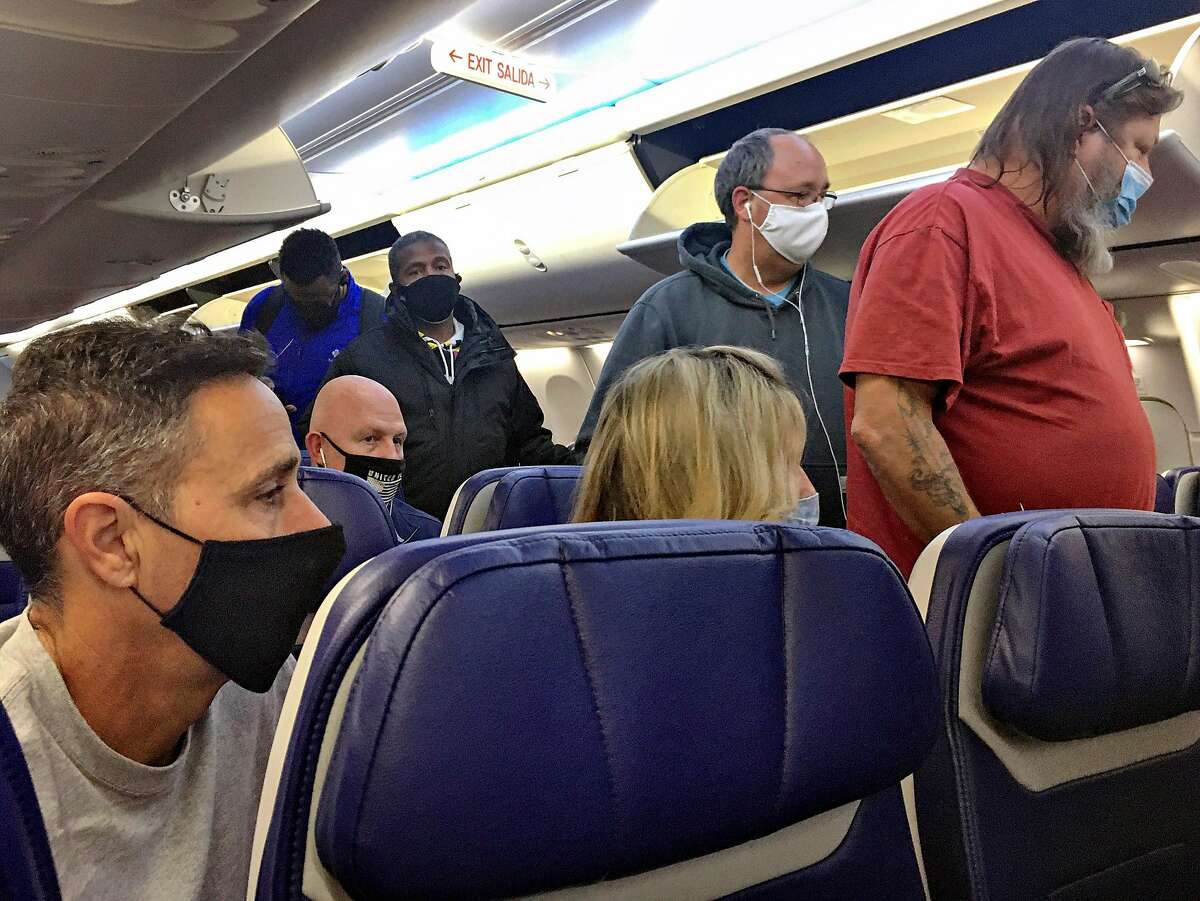 Masked passengers board a flight to Oakland on Nov. 15. Virus cases are increasing alarmingly, and holiday gatherings are likely to take another toll.