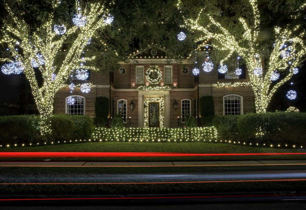 The rear lights of a car add to the festive nature of holiday decorations at this River Oaks home.