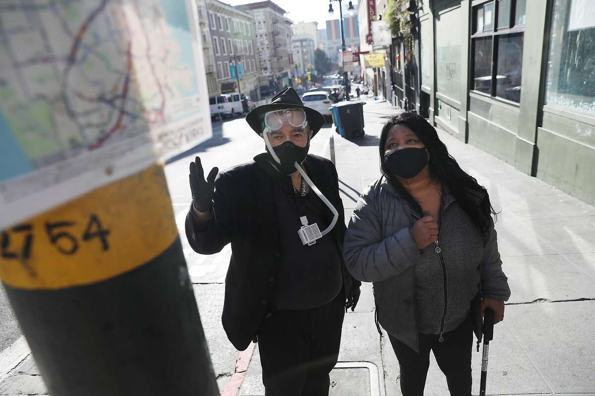 David Elliott Lewis (left), Central City SRO tenant advocate, and Cheryl Shanks of the Tenderloin Neighborhood Development Corporation examine signage at a Muni stop where they used to be able to catch the 27 line.