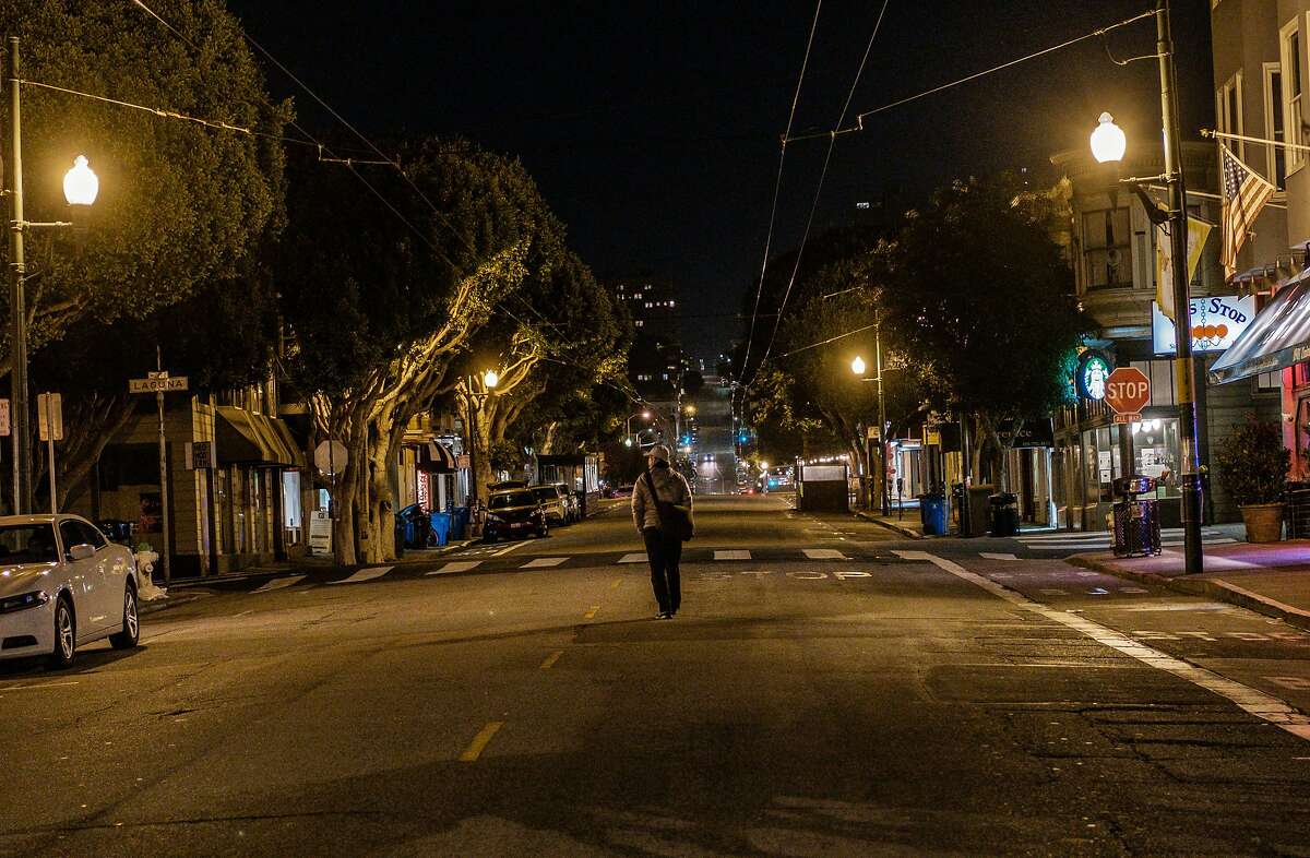 A pedestrian walks down the middle of Union Street as the mandatory 10 p.m. curfew takes effect in San Francisco on Monday, November 30, 2020.