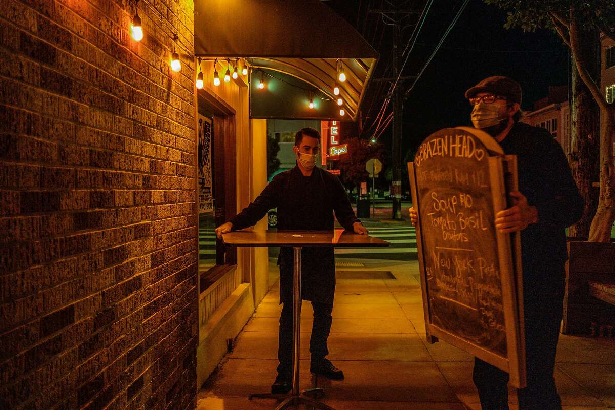 Ronnie Selak, left, and Dan O’Niell bring things indoors at Brazen Head just before the mandatory 10pm curfew takes effect in San Francisco on Monday, November 30, 2020.