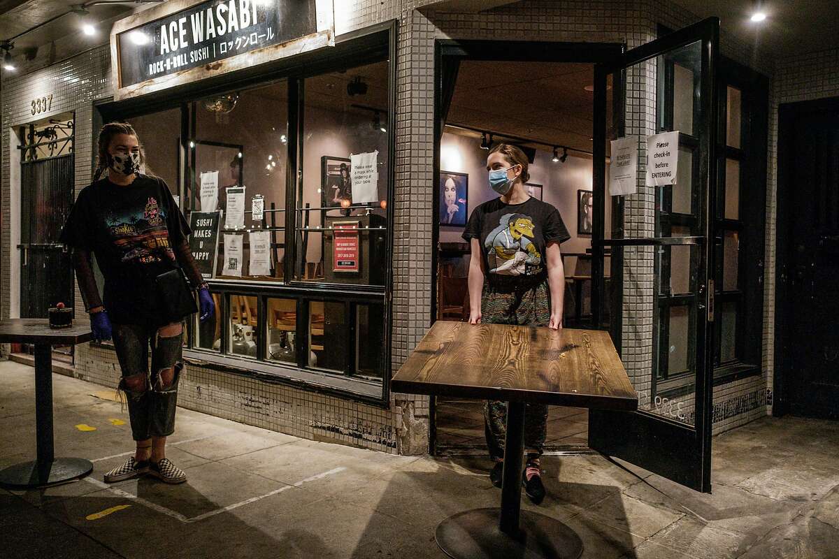 Megan McCann, left, and Miranda Lehr bring a tables indoors at Ace Wasabi just before the mandatory 10pm curfew takes effect in San Francisco on Monday, November 30, 2020.