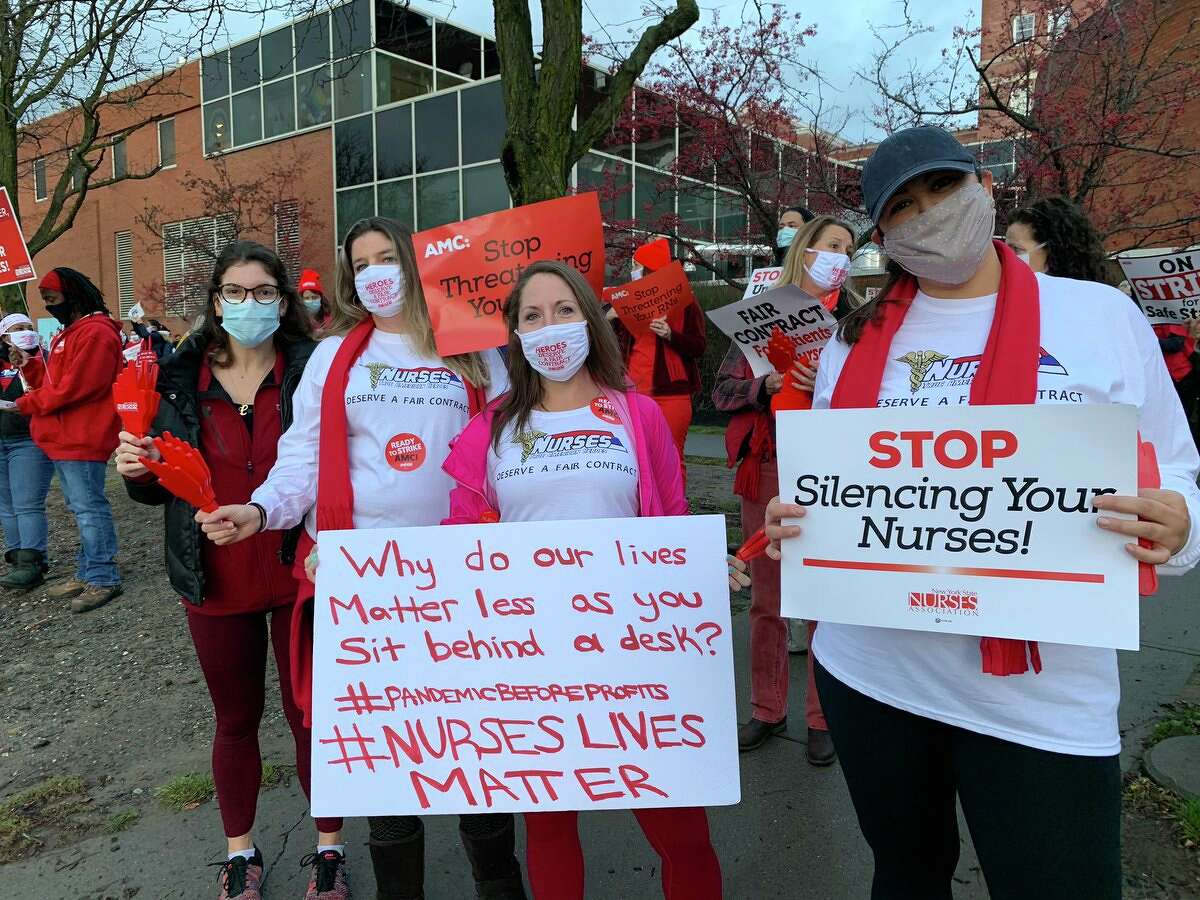 Albany Medical Center nurses pose with their signs. Mary-Elizabeth Moshier, center, said roughly 150 nurses were unable to join the picket line because they contracted COVID-19. The nurses union accuses the hospital of lax safeguards, and are particularly upset at having to reuse single-use masks.