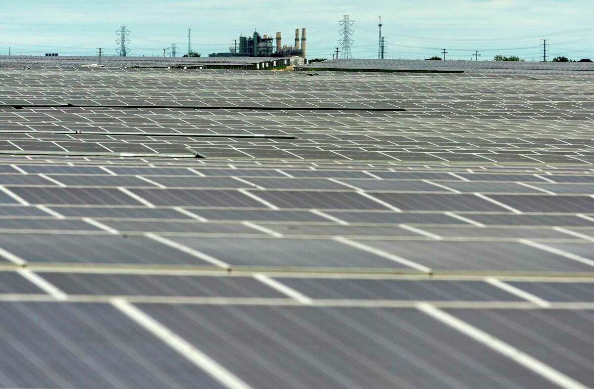 Fields of solar panels at OCI Solar Power's Alamo 1 Solar Farm are seen Sept. 23, 2020 as CPS Energy's coal-powered electric plant is seen in the background. CPS officials launched the “FlexPower Bundle” RFP this week seeking to add another 900 megawatts of solar power.