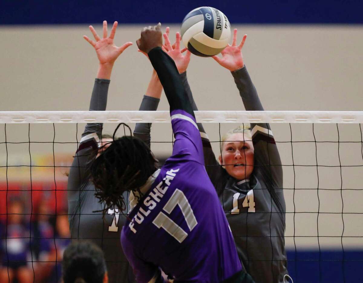 Magnolia middle blocker Ellie Anderson (14) blocks a shot by Fulshear outside hitter Brielle Warren (17) beside Magnolia outside hitter Marissa Moffatt (7) during the first set of a Region III-5A semifinal high school volleyball playoff match at Cypress Springs High School, Tuesday, Dec. 1, 2020, in Cypress.