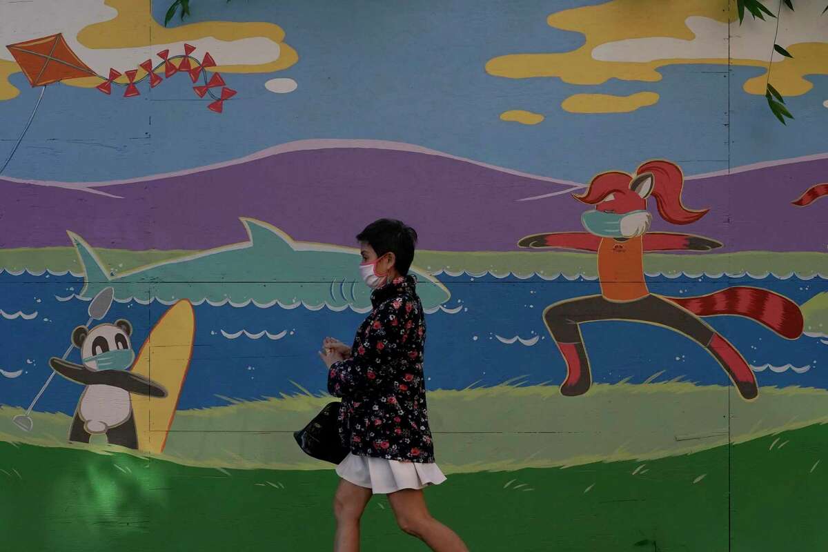 Un transeúnte porta una mascarilla mientras camina frente a un mural durante la pandemia de coronavirus en San José, California, el martes 1 de diciembre de 2020.