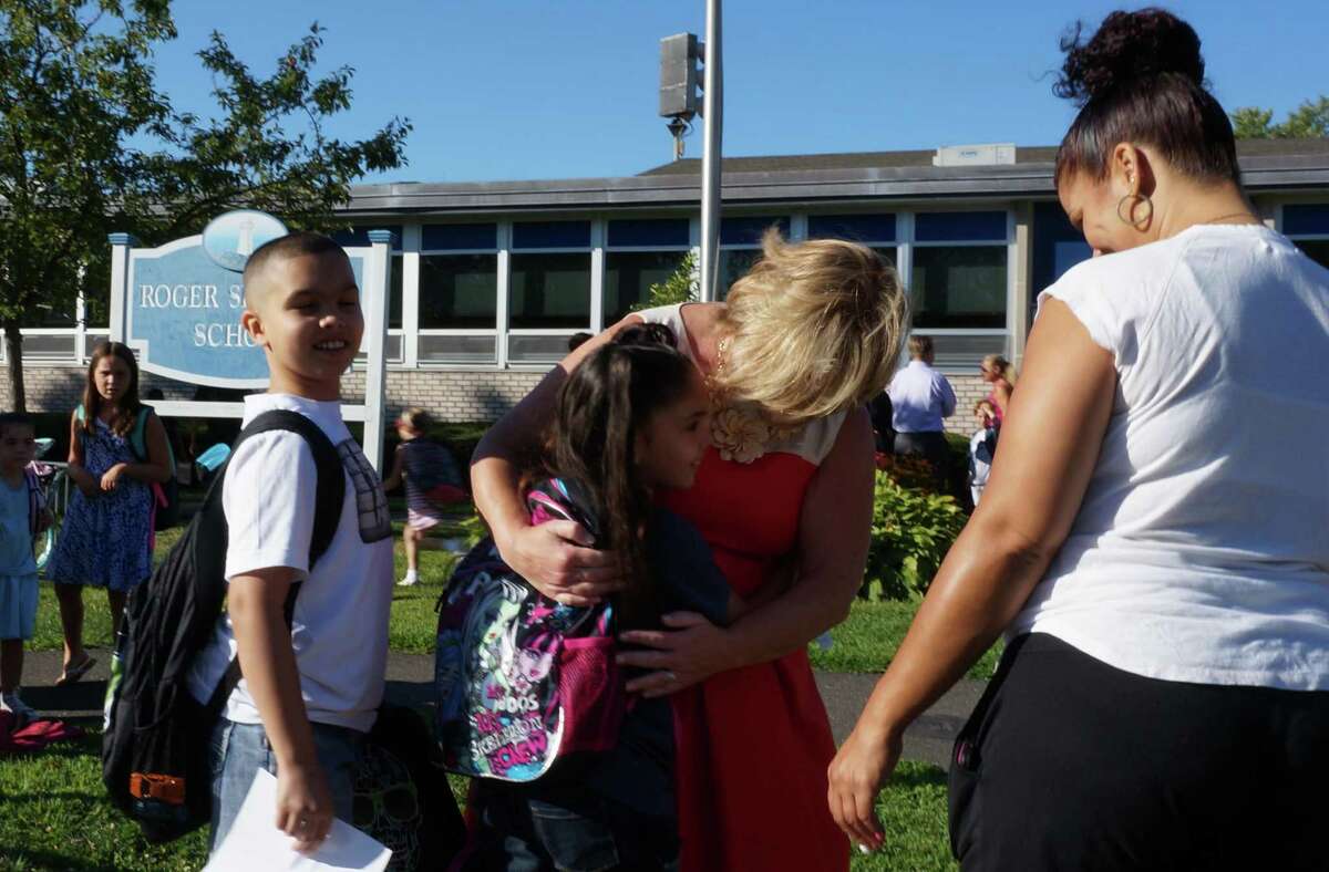 Returning Sherman School students get a hug from Principal Eileen Roxbee Thursday on the first day of school in 2014.