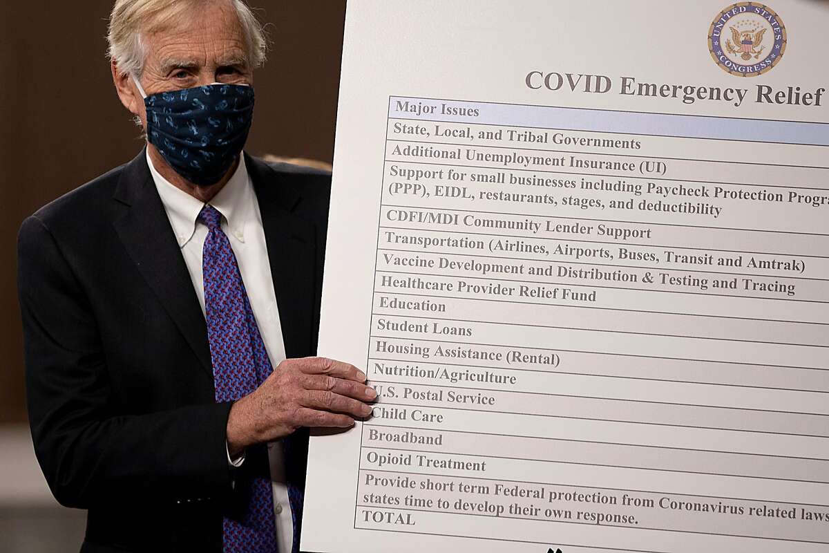 Sen. Angus King, a Maine independent,sets up a sign alongside a bipartisan group of Democrat and Republican members of Congress as they announce a compromise proposal for a COVID-19 relief bill on Dec. 1.