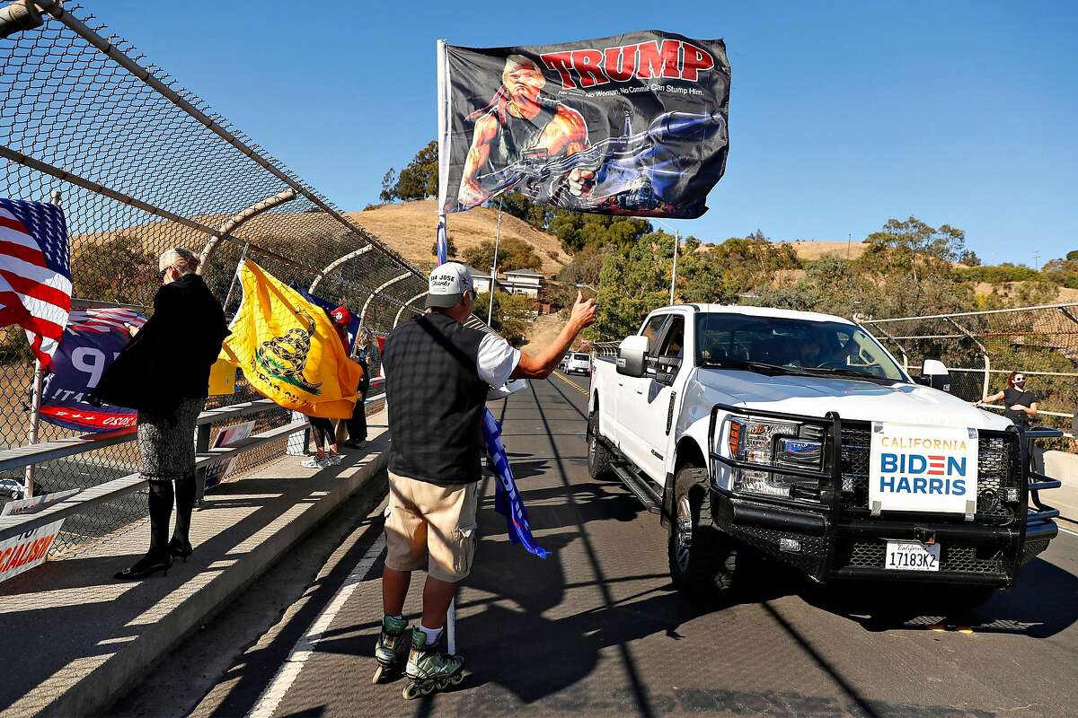 A supporter of President Trump waves as a President-elect Joe Biden supporter drives past on El Curtola Boulevard overpass over Highway 24 in Lafayette on Nov. 7.