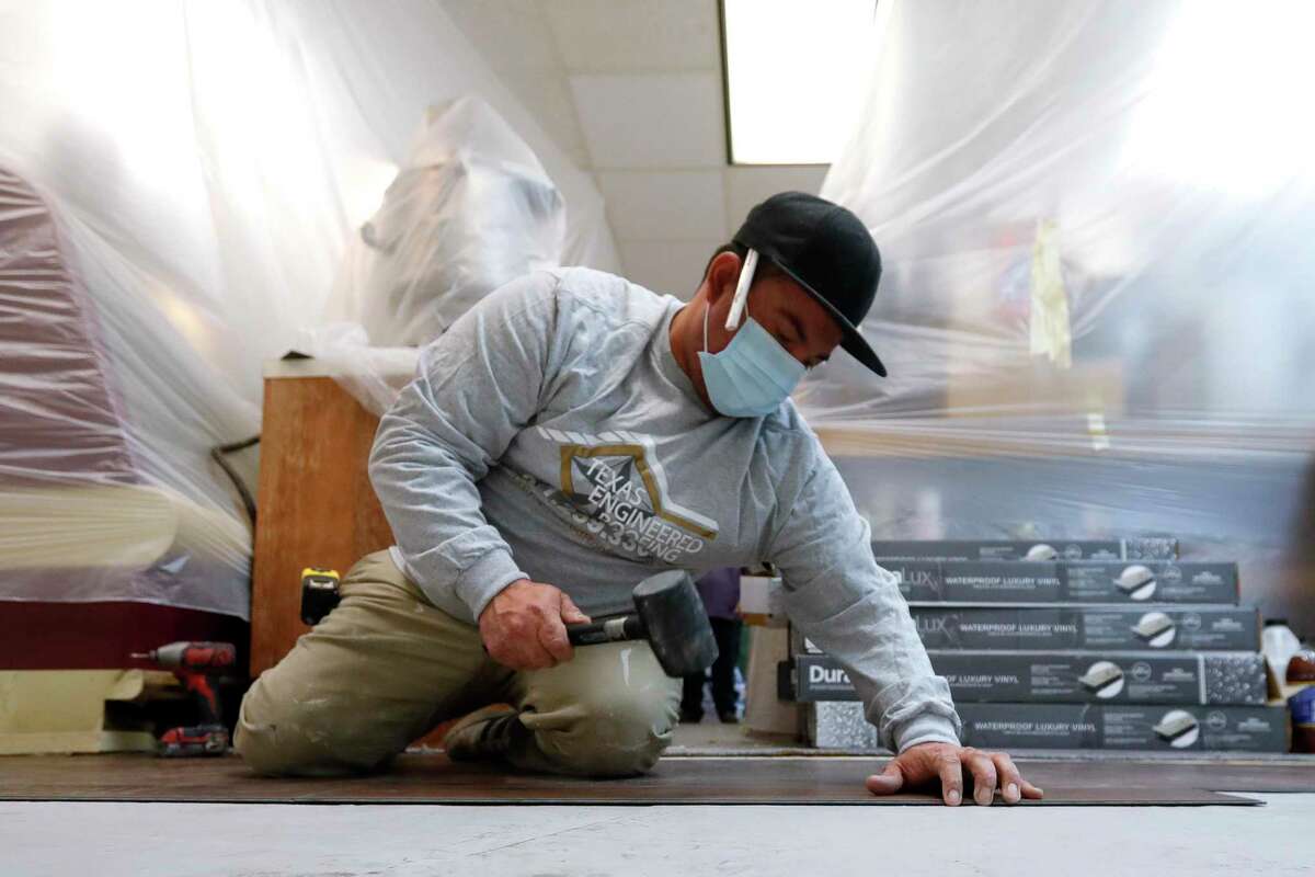 Carlos Rica, with Texas Engineering Roofing, helps install 440 square-feet of viynal flooring at The Candy House, Saturday, Nov. 28, 2020, in The Woodlands. A local company offered to install a new floor in the store for free as a community outreach project. The Candy House got a huge influx of business recently after a Facebook post went locally viral that incorrectly claimed the local business was in danger of closing.