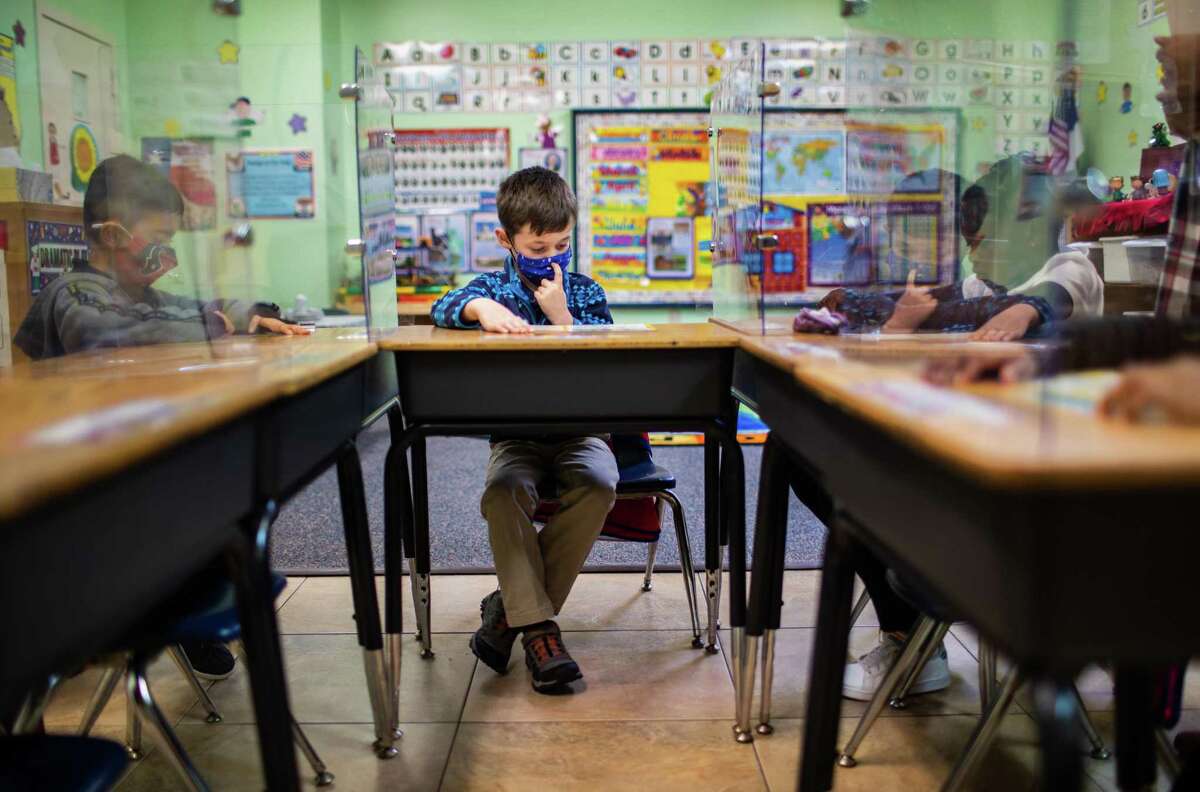 Spring Woods Christian Academy kindergarten Roen Morgan, 5, studies surrounded by his classmates and sneeze guard protectors in a classroom, Wednesday, Dec. 2, 2020, in Spring.