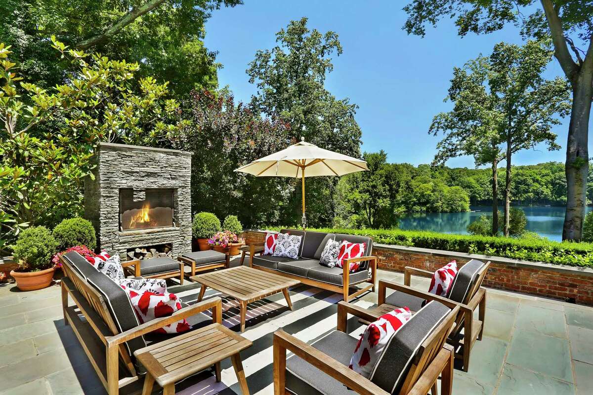 The six-bedroom brick manor at 7 Topping Lake is situated on 4.6 acres in a private association. The property enjoys a lakefront perspective and has several outdoor living areas, including this terrace, made especially cozy by the stacked-stone fireplace. Houlihan Lawrence is the listing brokerage for the $8.195 million estate.