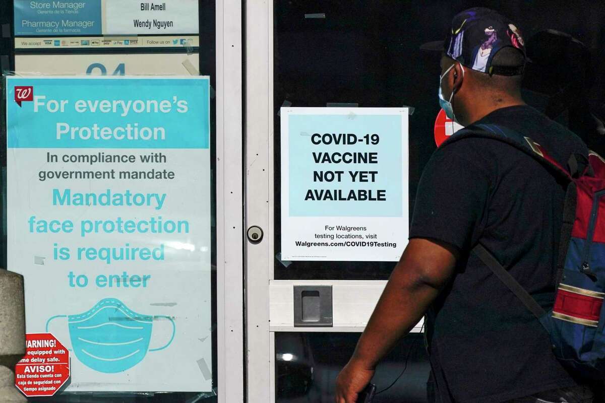 In this Dec. 2, 2020, file photo, a customer walks past a sign indicating that a COVID-19 vaccine is not yet available at Walgreens in Long Beach, Calif. (AP Photo/Ashley Landis, File)