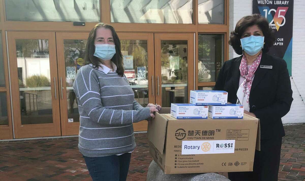 Susan Goldman, president of the Rotary Club of Wilton, presents Wilton Library's executive director Elaine Tai-Lauria with a donation of 1,700 face masks.