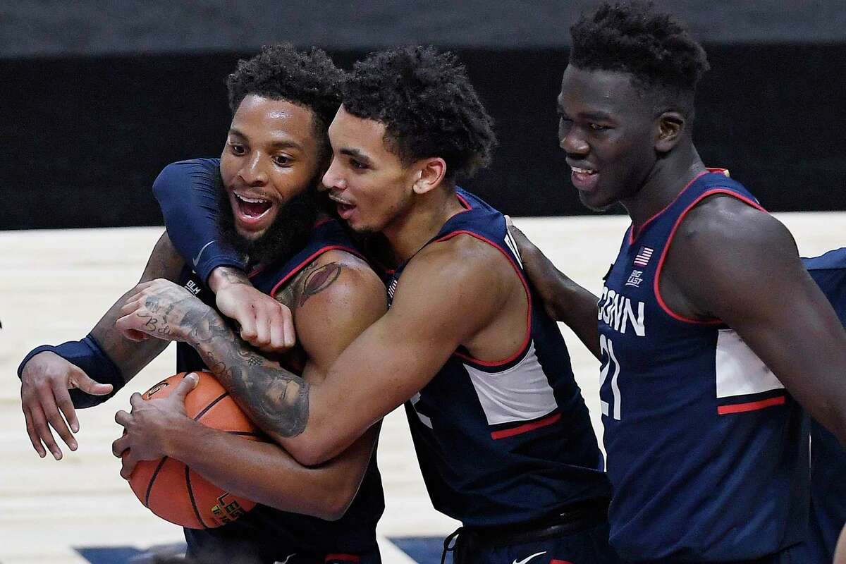 UConn’s James Bouknight, center, and Adama Sanogo, right, celebrate with R.J. Cole after Cole gained possession of the ball as the clock ran out in the Huskies’ win over Southern California on Thursday in Uncasville.