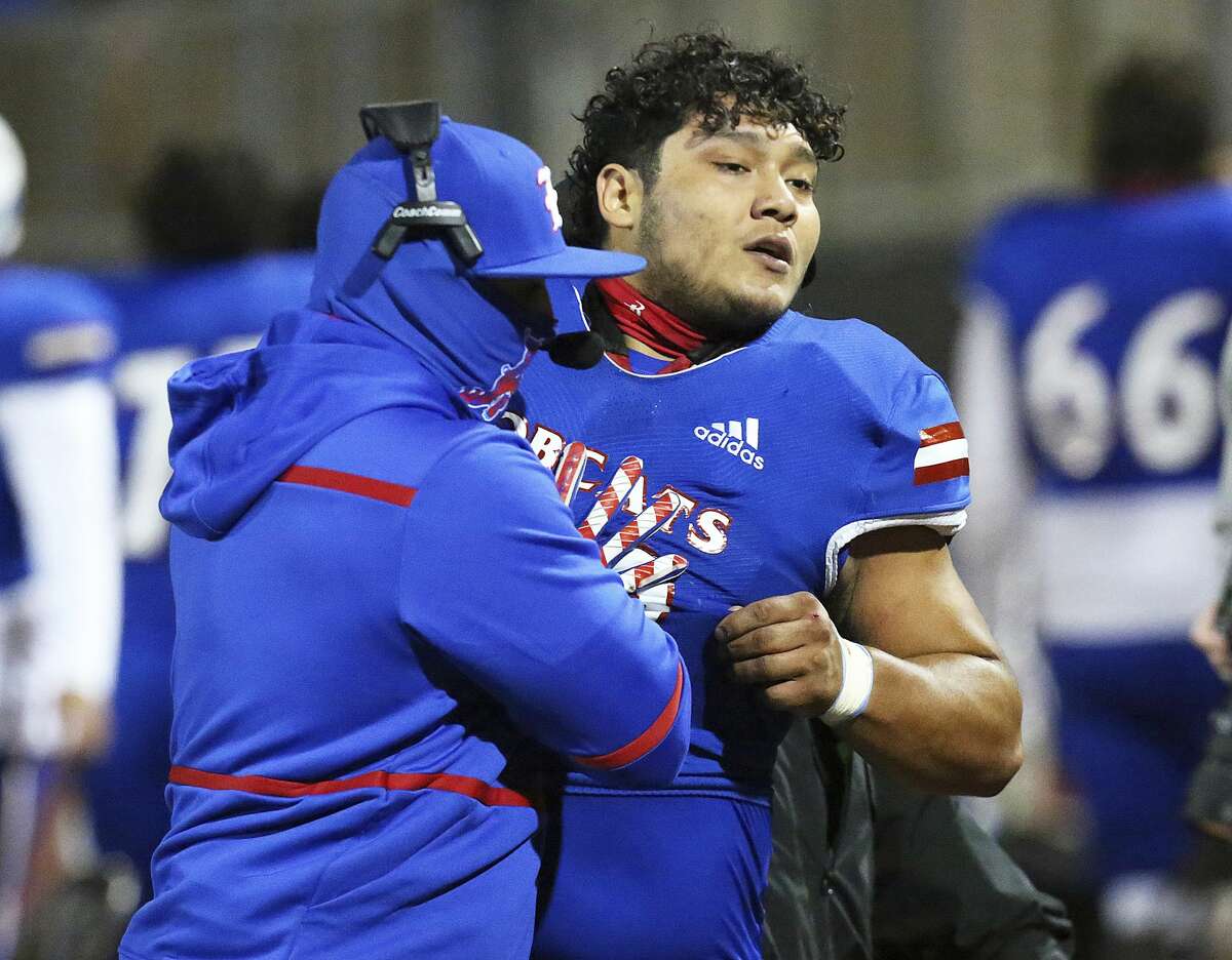Edinburg's Emmanuel Duron is pulled from the field by coaching staff after charging a referee during a high school football zone play-in game against Pharr-San Juan-Alamo on Thursday, Dec. 3, 2020, in Edinburg, Texas. Duron came running from the sideline area after the referee announced his ejection, slamming into the official. Duron was escorted from the stadium by police. (Joel Martinez/The Monitor via AP)