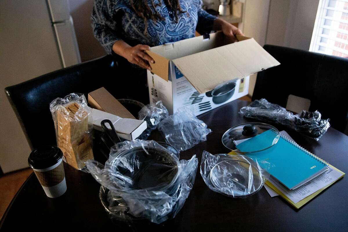 Shawn Landrum-Teppish unpacks a full kitchenware set while moving into her own apartment in San Francisco, Calif. Tuesday, December 1, 2020. Landrum-Teppish, who has been living in a city-funded hotel room for the past few months, moved into a new housing unit on December 1. This is the first time Landrum-Teppish has had permanent housing in ten years.