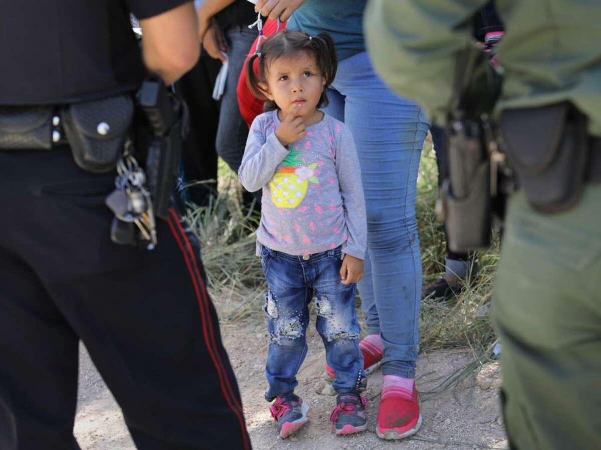A police officer and a U.S. Border Patrol agent watch over a group of Central American asylum seekers before taking them into custody near McAllen, Texas.