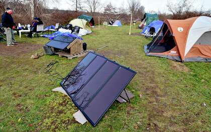 Solar panels at the West River encampment for the homeless near Ella Grasso Boulevard in New Haven on Dec., 2020. Mark Coville of the Amistad Catholic Workers House is at left.