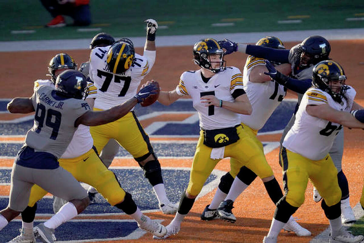 Iowa quarterback Spencer Petras is pressured by Illinois defensive lineman Owen Carney Jr. (99) and Roderick Perry II during the first half of an NCAA college football game Saturday, Dec. 5, 2020, in Champaign, Ill.