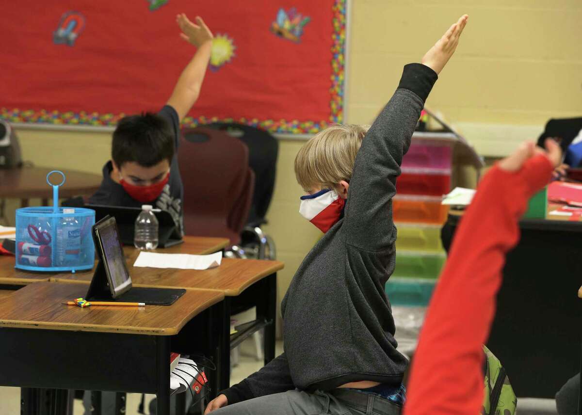Third-grader Logan Sapp (center) raises his arm to answer a question as students at Pearce Elementary at Southside ISD attend a combination of online and in-person class learning on Thursday, Dec. 3, 2020. According to Southside ISD Director of PR and Community Randy Escamilla, about half of the elementary school are currently in school and the other half are online as a result of the Coronavirus pandemic.