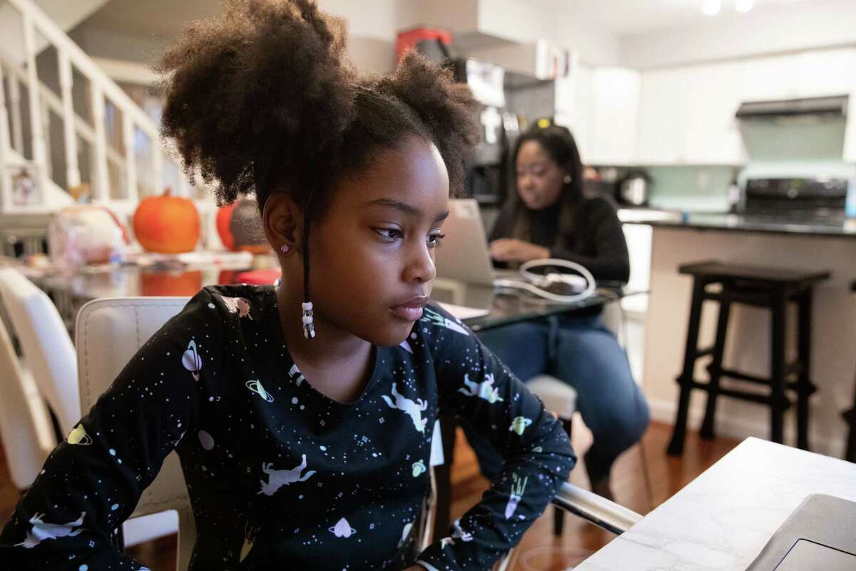 Olivia James attends virtual school while her mother, Karen James, works at their home in Alexandria, Va., on Oct. 29, 2020.
