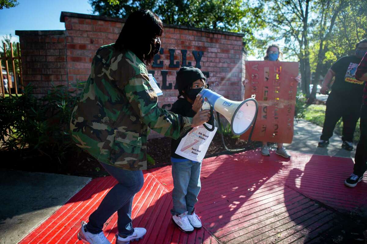 Kendra London helps her five year old son, Shahid, welcome participants to the Kelly Village apartments during a protest walk and rally opposing to the expansion of Interstate 45 in Fifth Ward on Dec. 6, 2020.