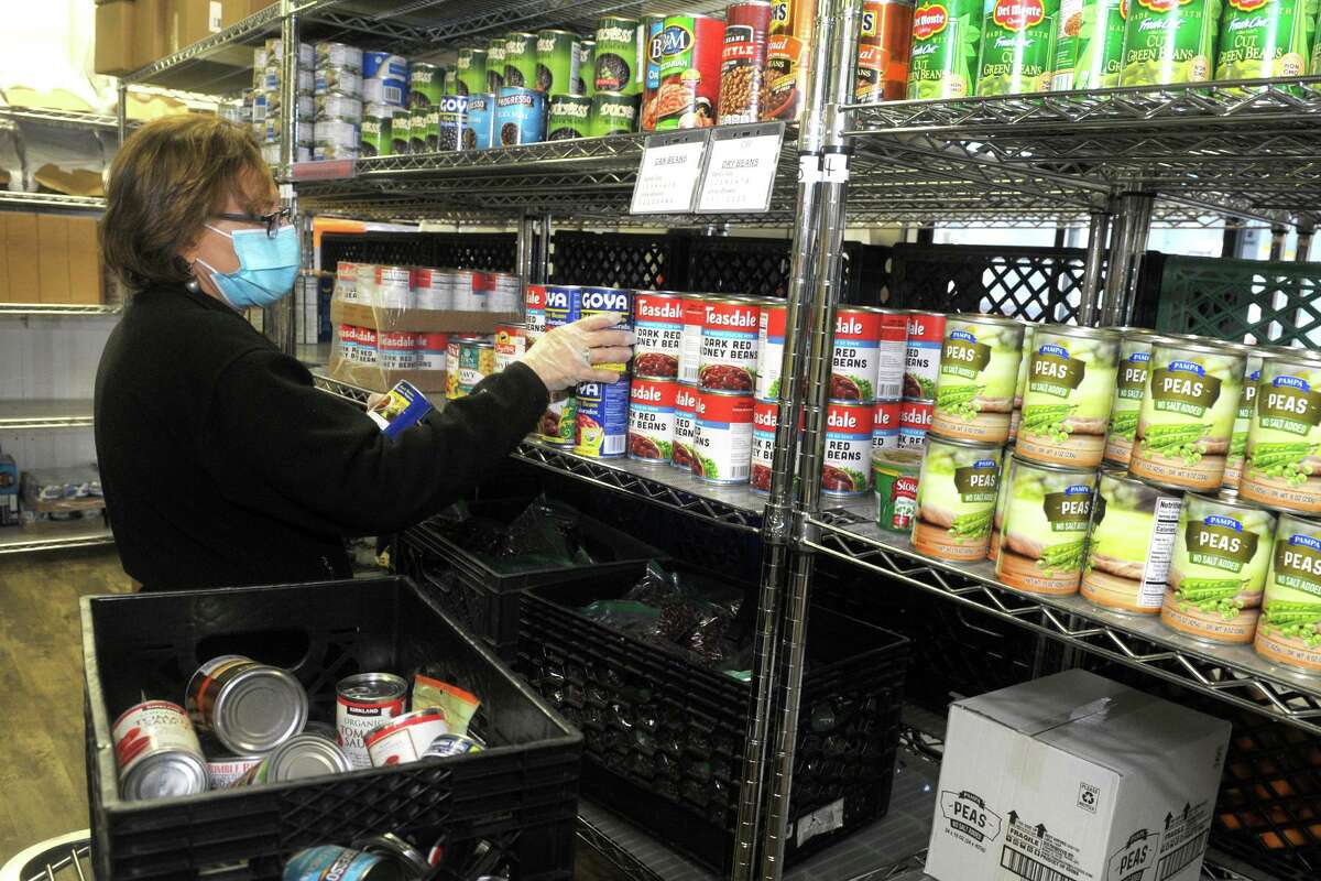 Volunteer Meryl Rhenfeld stocks the shelves with donated canned goods at the Person-to-Person food pantry in Norwalk, Conn. Nov. 17, 2020.