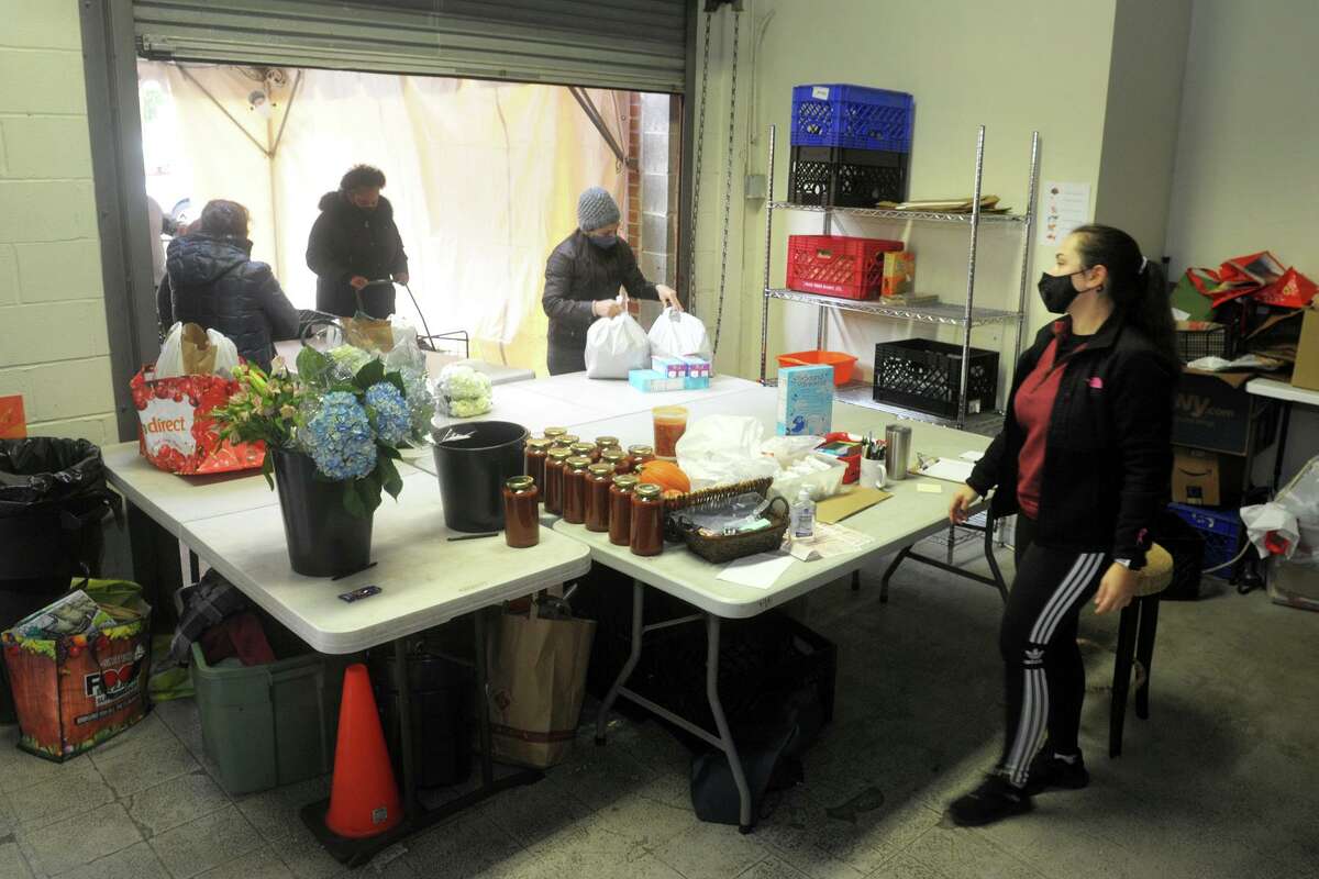 Volunteer Susana Alvarado, right, assists customers arriving to pick up food and groceries orders at the Person-to-Person food pantry in Norwalk, Conn. Nov. 17, 2020.