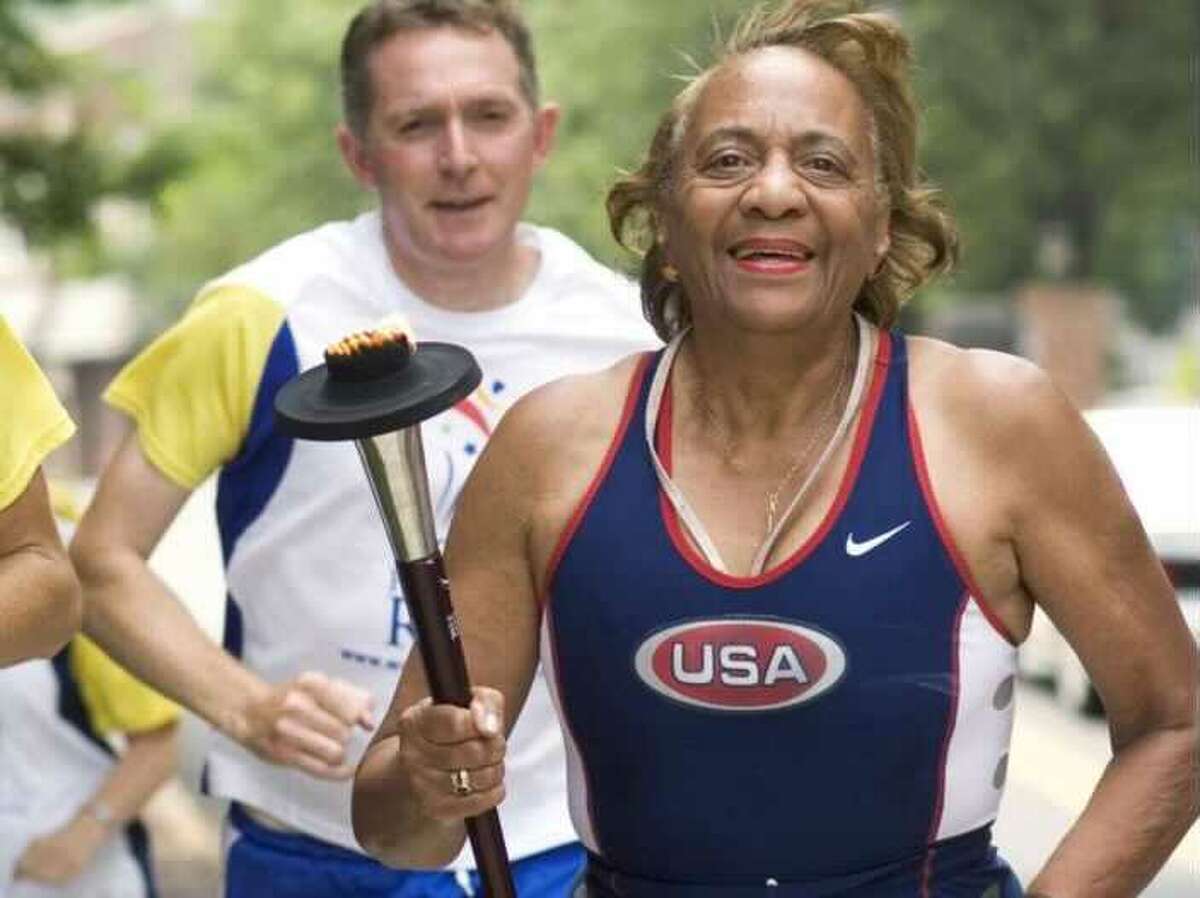 Mary Roman, former city clerk for the City of Norwalk, right, carries the torch during the World Harmony Run as it makes its way through Norwalk in 2008. Roman is trying to raise funds to compete in the World Masters Games in Australia.