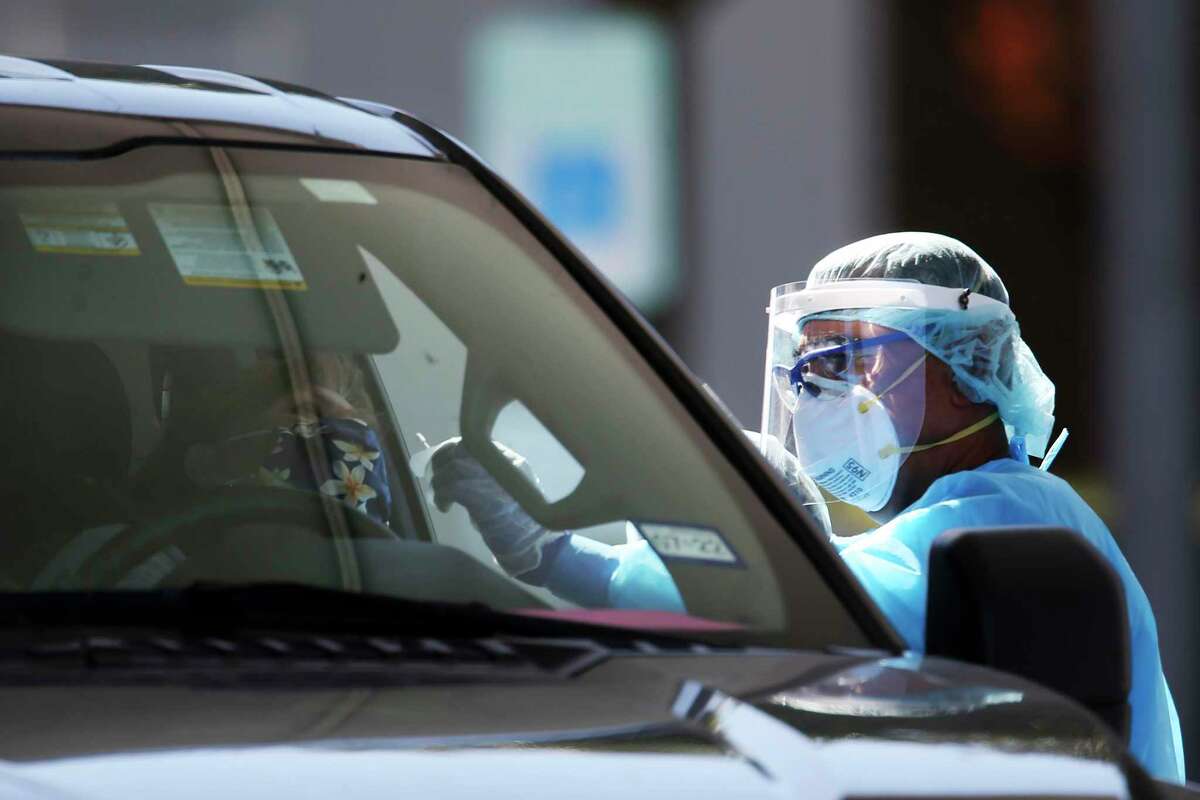 Personnel test a person at a COVID-19 drive-thru testing site at the CentroMed clinic on Palo Alto Road in November.