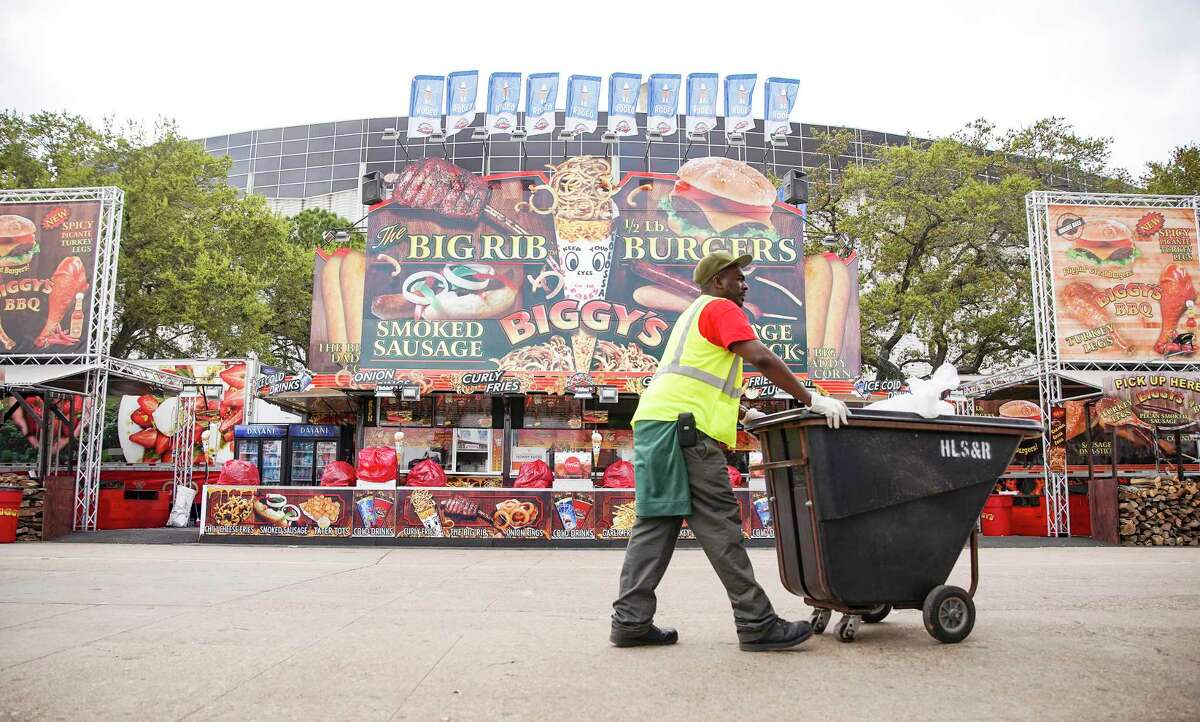 A worker picks up trash after the Houston Livestock Show and Rodeo announcement of the rodeo closing early on Wednesday, March 11, 2020.