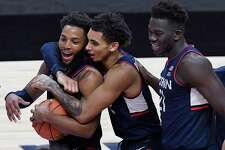 Connecticut's James Bouknight, center, and Adama Sanogo, right, celebrate with R.J. Cole after Cole gained possession of the ball as the clock ran out at the end of an NCAA college basketball game against Southern California, Thursday, Dec. 3, 2020, in Uncasville, Conn. (AP Photo/Jessica Hill)