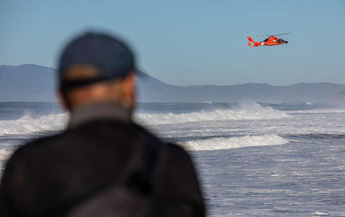 A U.S. Coast Guard helicopter flys low near the Pacifica Pier, in Pacifica, Calif. The National Weather Service issued a high surf warning as a massive swell crashed against the Bay Area coastline on Tuesday, Dec. 8, 2020.