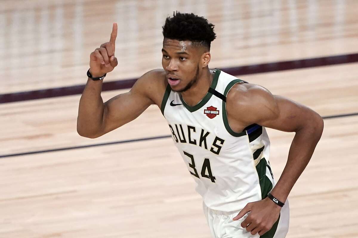 FILE - Milwaukee Bucks' Giannis Antetokounmpo (34) celebrates after a dunk against Orlando during the first half of an NBA basketball first round playoff game Saturday, Aug. 29, 2020, in Lake Buena Vista, Fla., in this Saturday, Aug. 29, 2020, file photo. Jrue Holiday is eager to contend for a title in Milwaukee alongside two-time reigning MVP Giannis Antetokounmpo. The Bucks acquired Holiday as their major offseason addition as they attempt to entice Antetokounmpo to accept a supermax extension that will keep him in Milwaukee for years to come.(AP Photo/Ashley Landis, File)