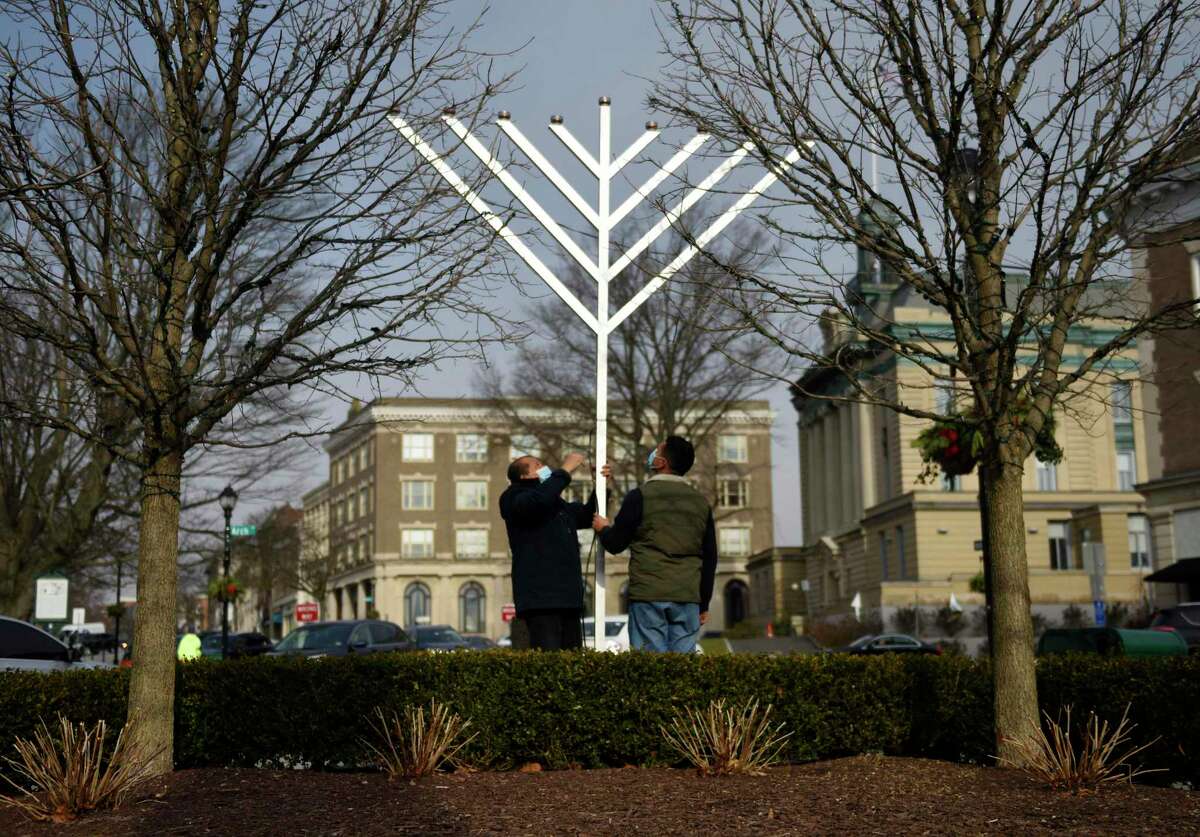 Bernard Garcia, left, and Edras Sand install a giant menorah from Chabad Lubavitch of Greenwich at the intersection of Greenwich Avenue and Arch Street in Greenwich on Dec. 9. Hanukkah started Dec. 10 and lasts through Dec. 18.