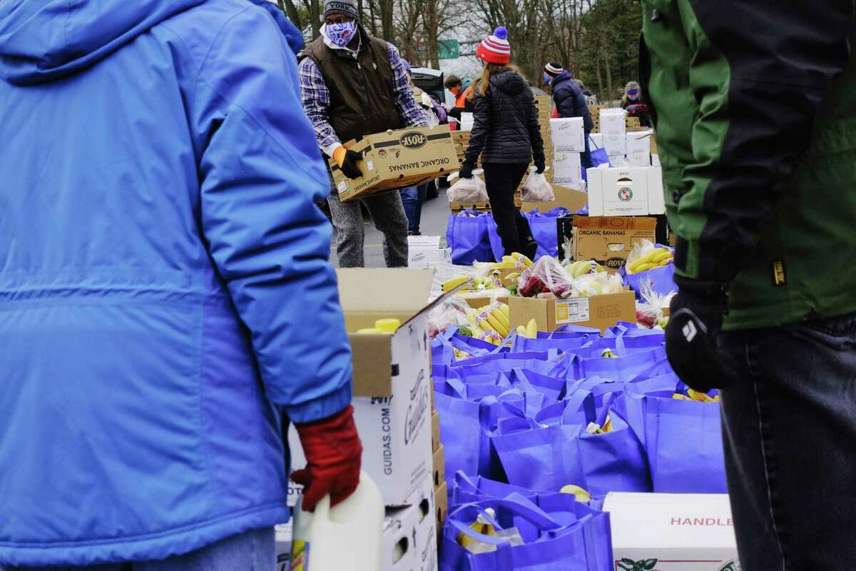 Volunteers load food into vehicles during a mass food distribution put on by Catholic Charities of the Diocese of Albany, and the Regional Food Bank of Northeastern New York on Thursday, Dec. 10, 2020, in Schenectady, N.Y. The next mass food distributions will be on Monday Dec. 14th, at Metropolitan Church, located at 105 2nd St, in Albany, and then on Wednesday, Dec. 16th, at SUNY Schenectady college. Both events begin at 9:30AM. The distribution is open to the public and no pre-registration is required. Food is distributed on a first-come, first-served basis, and the distribution will last until supplies are gone. (Paul Buckowski/Times Union)