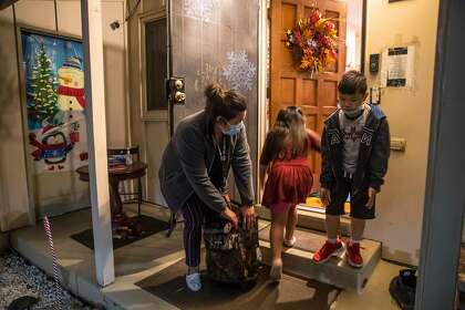 Krystal Oliva picks up her kids, Maureen Oliva, 5, and Kenzo Reeves, 8, at Wishing Well Daycare in Hayward, Calif., on Wednesday, December 9, 2020. Fouziya Bawazir runs a 24-hour day care center in her home in Hayward. She takes care of 15 kids, from five families. 10 are there during the day and five come overnight while their single parents work graveyard.
