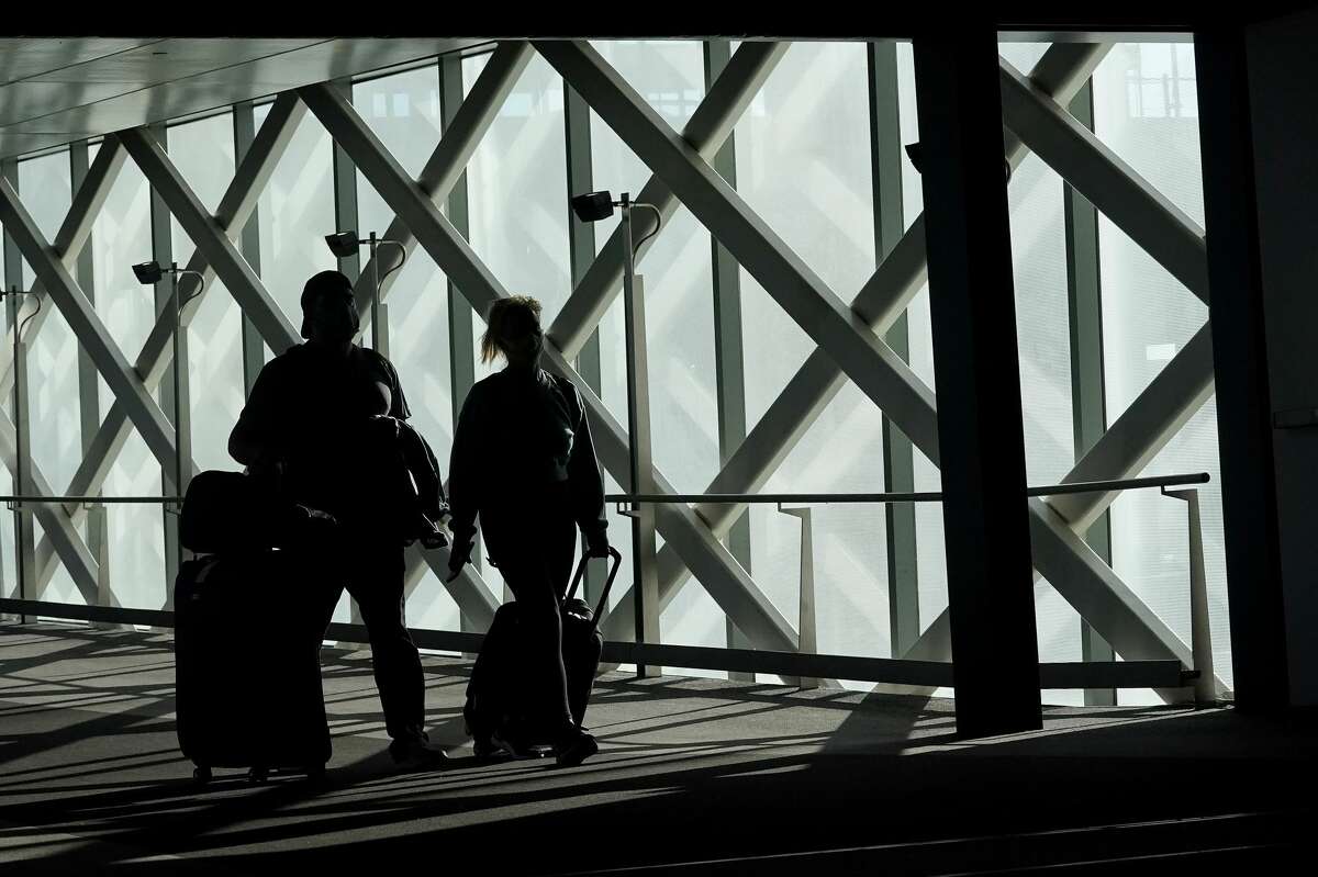 Travelers walk toward terminals at San Francisco International Airport during the coronavirus outbreak in San Francisco, Tuesday, Nov. 24, 2020.