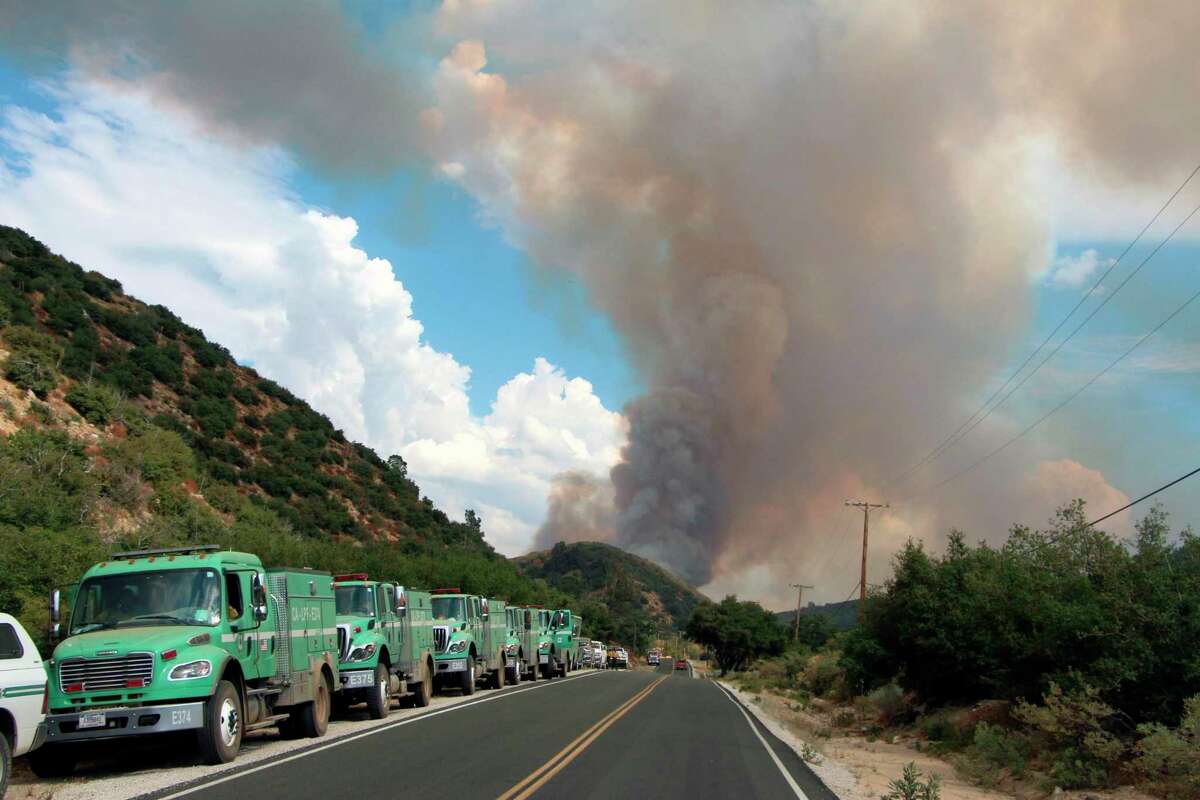 Support vehicles parked along Pine Canyon Road, north of Los Angeles, California, while the Lake Fire is visible in the background. (Judy Nathan/U.S. Forest Service Photo)
