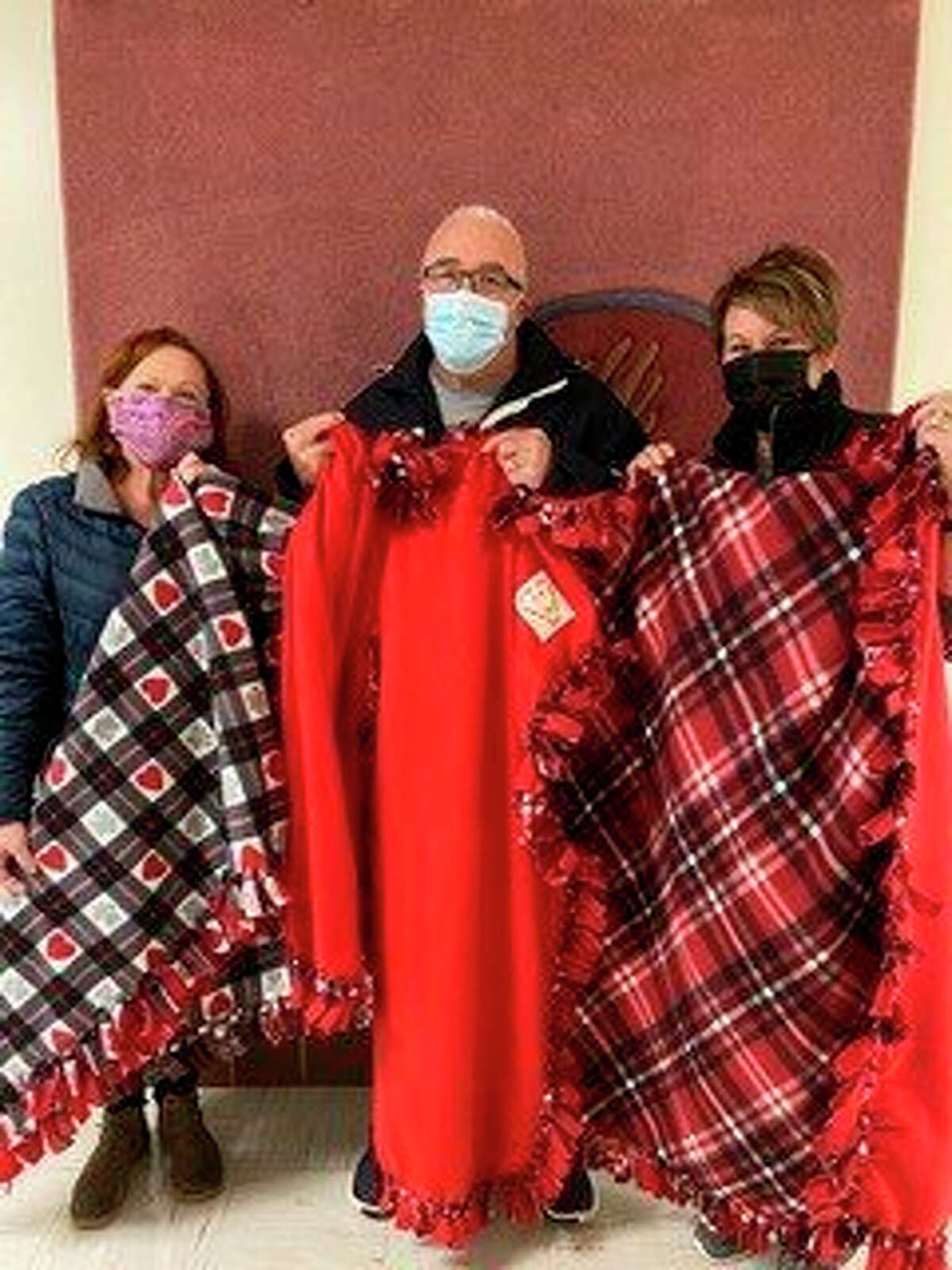 Midland Community Former Offenders Advocacy's executive director Rob Worsley, middle, accepts fleece blankets made by the Ladies of Blessed Sacrament recently made and donated fleece blankets for his organization. (Photo provided)