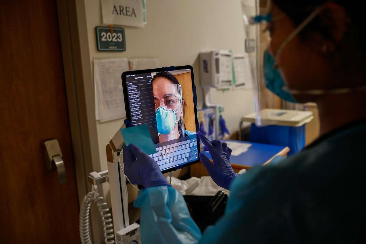 Nurse Janessa Deleon sets up a tablet on a wheeled pole so a COVID-19 patient can do a video chat with family members.