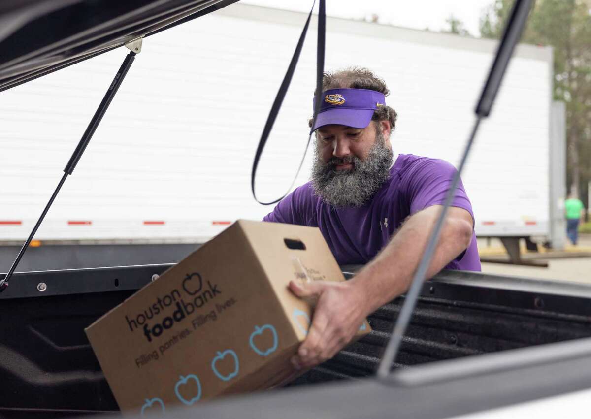 Brock Hivnor loads food into the back of a truck during a food distribution event at The Ark Church, Saturday, Dec. 12, 2020, in Conroe. Hivnor has been a member of the church for the last 8 years and has volunteered for various events for the past 3 years.