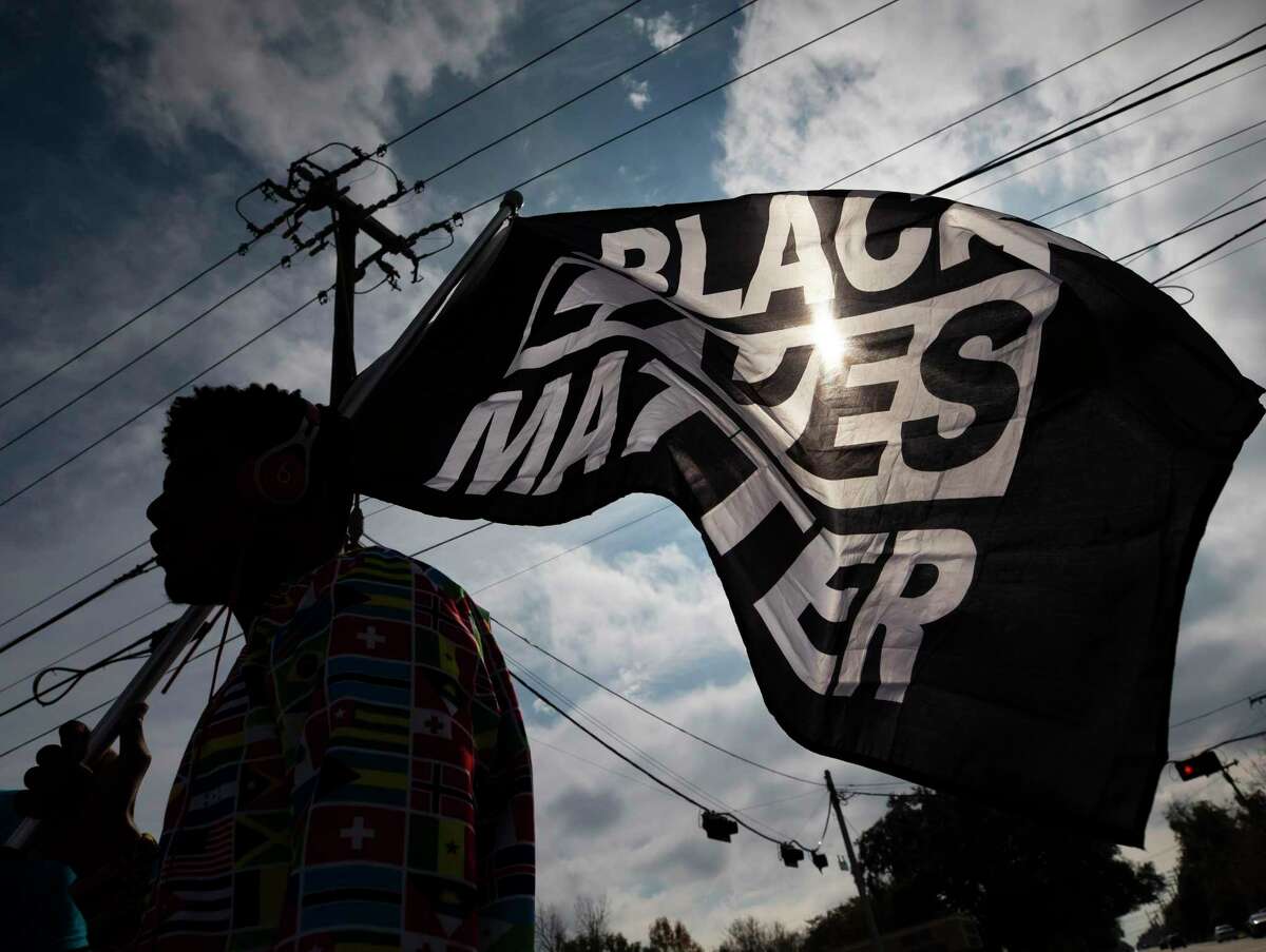 MD Crawford carries a Black Lives Matter flag before a march in La Marque, Texas on Saturday, Dec. 12, 2020, to protest the shooting of Joshua Feast, 22, by a La Marque police officer. Officials say Officer Jose Santos fatally shot Feast late Wednesday. (Stuart Villanueva /The Galveston County Daily News via AP)
